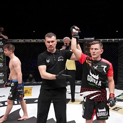 Рефери поднимает руку победителя в клетке на турнире EFC